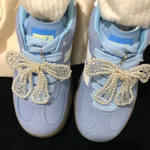 Detailed view of elegant pearl bow-shaped shoe charms attached to light blue sneakers