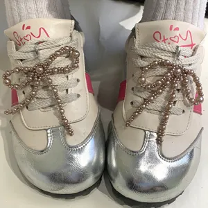 Vue détaillée de breloques en perles en forme de nœud sur des lacets de baskets.
