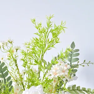 Vue détaillée de fleurs de mariage artificielles blanches avec un feuillage vert.