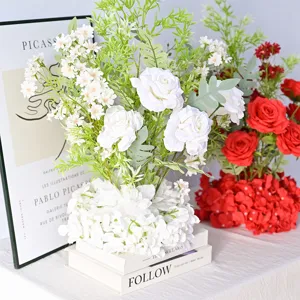 Vue détaillée de compositions florales artificielles blanches et rouges sur des livres.
