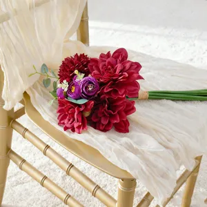 Elegant kunstmatig bruidsboeket met rode dahlia's en paarse bloemen op een gouden stoel.