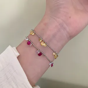 Dettaglio di due braccialetti a catena di sfere d'argento con zirconi a goccia colorati