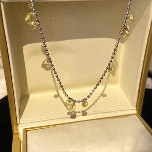 Dettaglio di una collana a sfere d'argento con brillanti zirconi gialli a goccia d'acqua