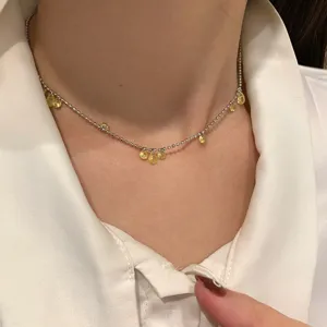 Dettaglio di una collana a sfere d'argento con pendenti in zircone giallo a goccia.