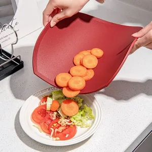 Flexible red D-shaped plastic cutting board for kitchen use with sliced carrots