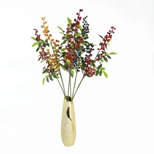 Artificial berry branches in red yellow blue colors in a gold vase for home decor