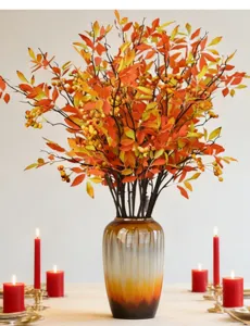 Detailed view of autumn artificial Nandina berry branches in a ceramic vase with red candles