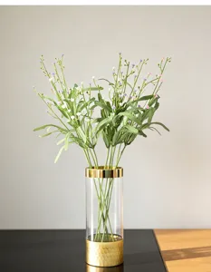 Détail de bouquet de fleurs artificielles de gypsophile dans un vase en verre doré.