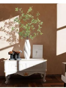 Künstlicher grüner Eukalyptuszweig in weißer Vase auf klassischem Schrank mit Sonnenlichtschatten
