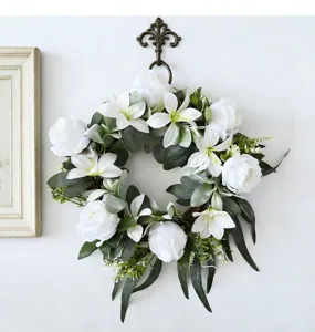 Detailed macro view of handmade white rose and lily wreath with lush green foliage