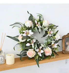 Detailed view of artificial rose and lily wreath displayed on a wooden shelf