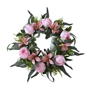Detailed view of an artificial pink rose and lily wreath for home wall decoration.