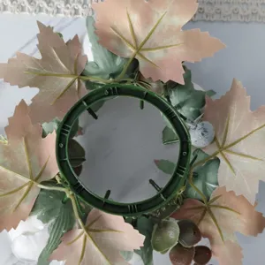 Detailed view of the green plastic base and maple leaves of an artificial candle wreath