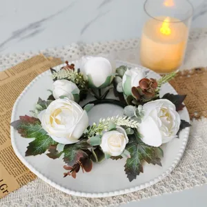 Detailed view of a white rose and maple leaf candle ring wreath on an elegant dinner plate