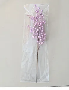 Dettaglio di ramo di bacche rosa glitterate in confezione di plastica trasparente