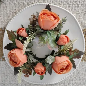 Close-up of orange artificial rose and maple leaf wreath on a white decorative plate