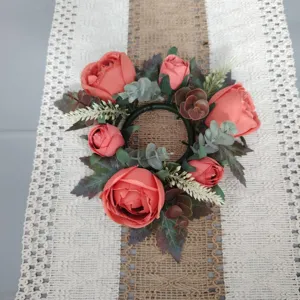 Top-down view of an artificial rose and maple leaf candle holder wreath decoration.