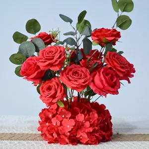 Gros plan détail arrangement floral de roses rouges artificielles avec feuilles d'eucalyptus.