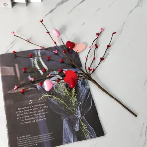 Detailansicht eines dekorativen Zweigs mit roten und rosa Herzknospen auf Marmor.