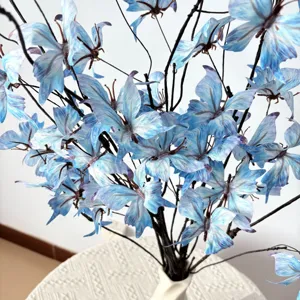 Nahaufnahme von künstlichen blauen Schmetterlingsblumen auf dekorativen Zweigen