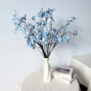 Detailansicht blauer künstlicher Schmetterlingsblumen in einer weißen Vase auf einem Tisch