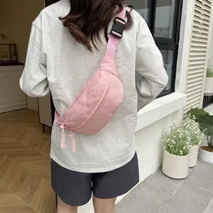 Détails du sac de poitrine rose en nylon montrant le porté croisé et large sangle.