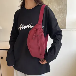 Vue détaillée du sac de poitrine minimaliste en nylon bordeaux avec tirettes de zipp tressées.