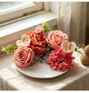 Dettaglio di fiori finti in seta con rose rosa e peonie disposti su un piatto bianco.
