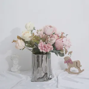 Vista detallada de un ramo de rosas y hortensias artificiales en un jarrón de plata