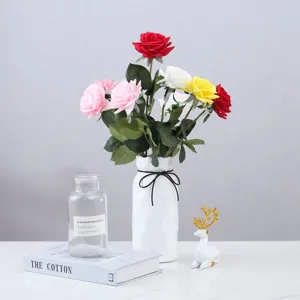 Vue détaillée de roses artificielles colorées dans un vase blanc avec des accessoires