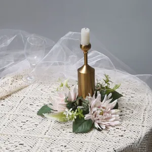 Corona di candele con crisantemi artificiali e portacandele dorato su tovaglia di pizzo