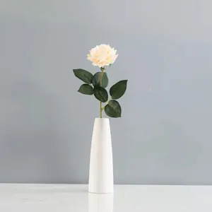 Rose artificielle élégante de couleur crème dans un vase minimaliste en céramique blanche