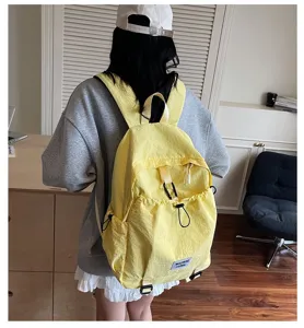 Back view of a student wearing a yellow large capacity casual backpack in a room.