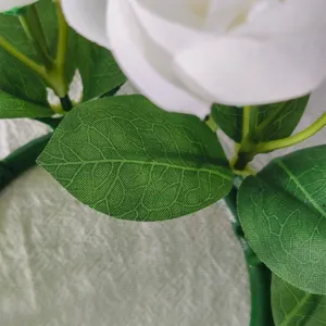 Detailed close-up showing the realistic green leaf texture of the artificial tea rose wreath.