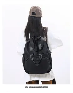 Détail du sac à dos en nylon noir montrant un design spacieux et des poignées.