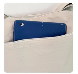 Primo piano dettagliato della borsa in nylon beige che mostra grande capacità di carico.