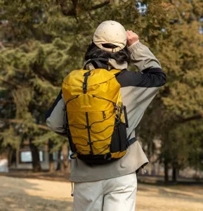 Outdoor action shot of model wearing a large yellow waterproof hiking backpack