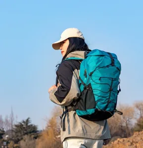 Detailed side view of a teal waterproof hiking backpack in an outdoor mountain scene