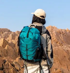 Large waterproof outdoor hiking backpack in blue-green shown in a rocky mountain landscape