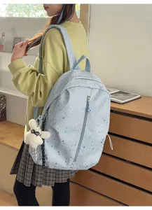 Mochila azul claro con patrón de estrellas y colgante de conejo usada por una modelo