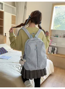 Vista trasera de una estudiante con mochila azul claro de estrellas en una habitación
