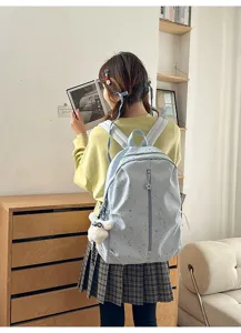 Mujer joven con una mochila azul claro de estrellas en un entorno interior moderno.