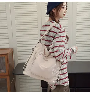 Dettaglio della borsa a tracolla da donna in morbido beige con tasca a cuore e robuste cerniere.
