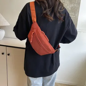 Vue détaillée du sac banane en nylon, montrant le tissu orange, la sangle et la fermeture.