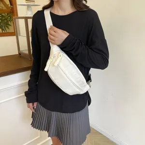 Vue détaillée du sac de poitrine décontracté en nylon blanc porté, avec fermeture éclair.