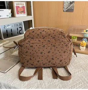 Vista trasera detallada de una mochila de pana marrón con estampado de lazos y corazones