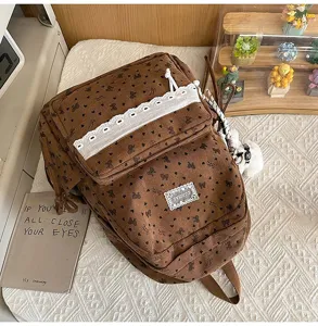 Vista detallada de la mochila de pana marrón con encaje blanco y flores.