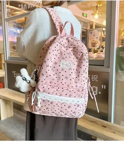 Primer plano de mochila de pana rosa con diseño de lazos y encaje en una modelo