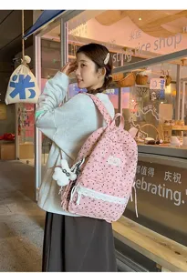 Chica asiática con mochila rosa de estilo preppy con lazos en una tienda de lifestyle