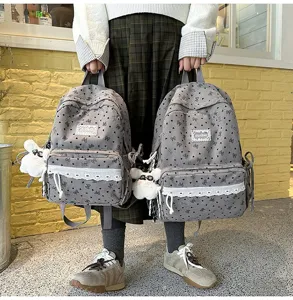 Vista de detalle de dos mochilas de pana gris con patrones de corazones y adornos de encaje